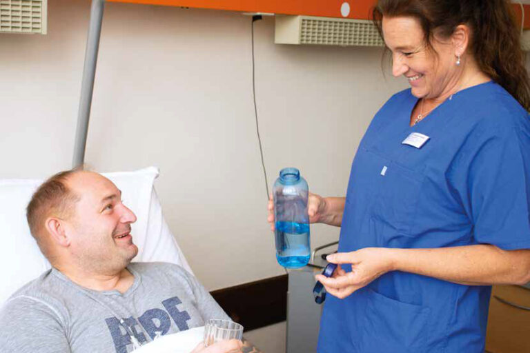 Titelbild Ihre Sprechzeit 2024/1 Titelbild des Gesundheitsmagazins "Ihre Sprechzeit" 2024-1: Eine Pflegekraft reicht einem Patienten Wasser.