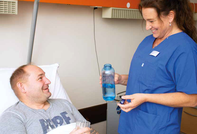 Titelbild Ihre Sprechzeit 2024/1 Titelbild des Gesundheitsmagazins "Ihre Sprechzeit" 2024-1: Eine Pflegekraft reicht einem Patienten Wasser.