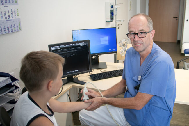 Dr. Ulrich Altrup bei der Ultraschalluntersuchung Dr. Ulrich Altrup untersucht den Arm eines jungen Patienten per Ultraschall