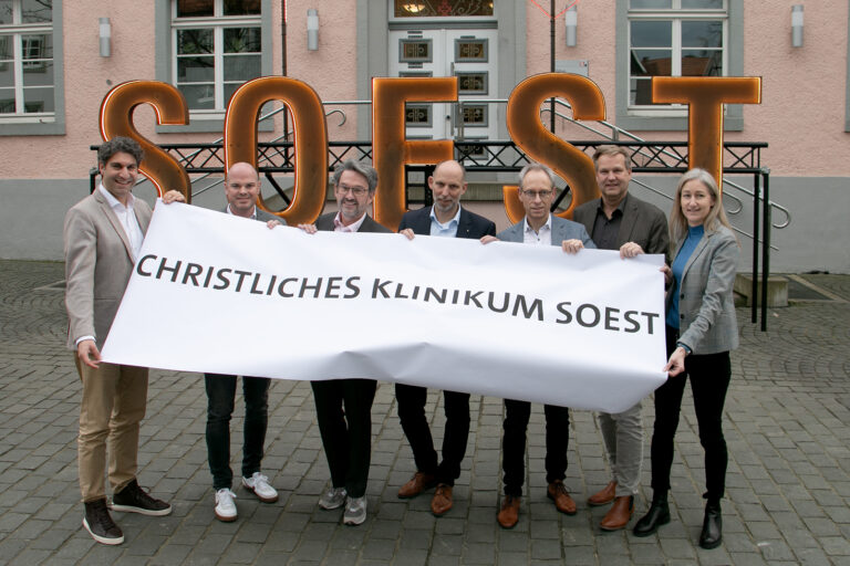 Fortschritte Krankenhaus-Fusion Das Bild zeigt (v.l.): Christan Schug (Geschäftsführer KlinikumStadtSoest), Tobias Franke (Kfm. Direktor Marienkrankenhaus Soest), Dr. Eckhard Ruthemeyer (Bürgermeister Stadt Soest), Christian Larisch (Geschäftsführer Hospitalverbund), Guido Ponto (Vorsitzender Verwaltungsrat Hospitalverbund), Thorsten Roy (Geschäftsführer Christliches Klinikum Unna) und Sabine Boschert (Kfm. Direktorin KlinikumStadtSoest). Sie halten gemeinsam ein Banner mit der Aufschrift "Christliches Klinikum Soest".